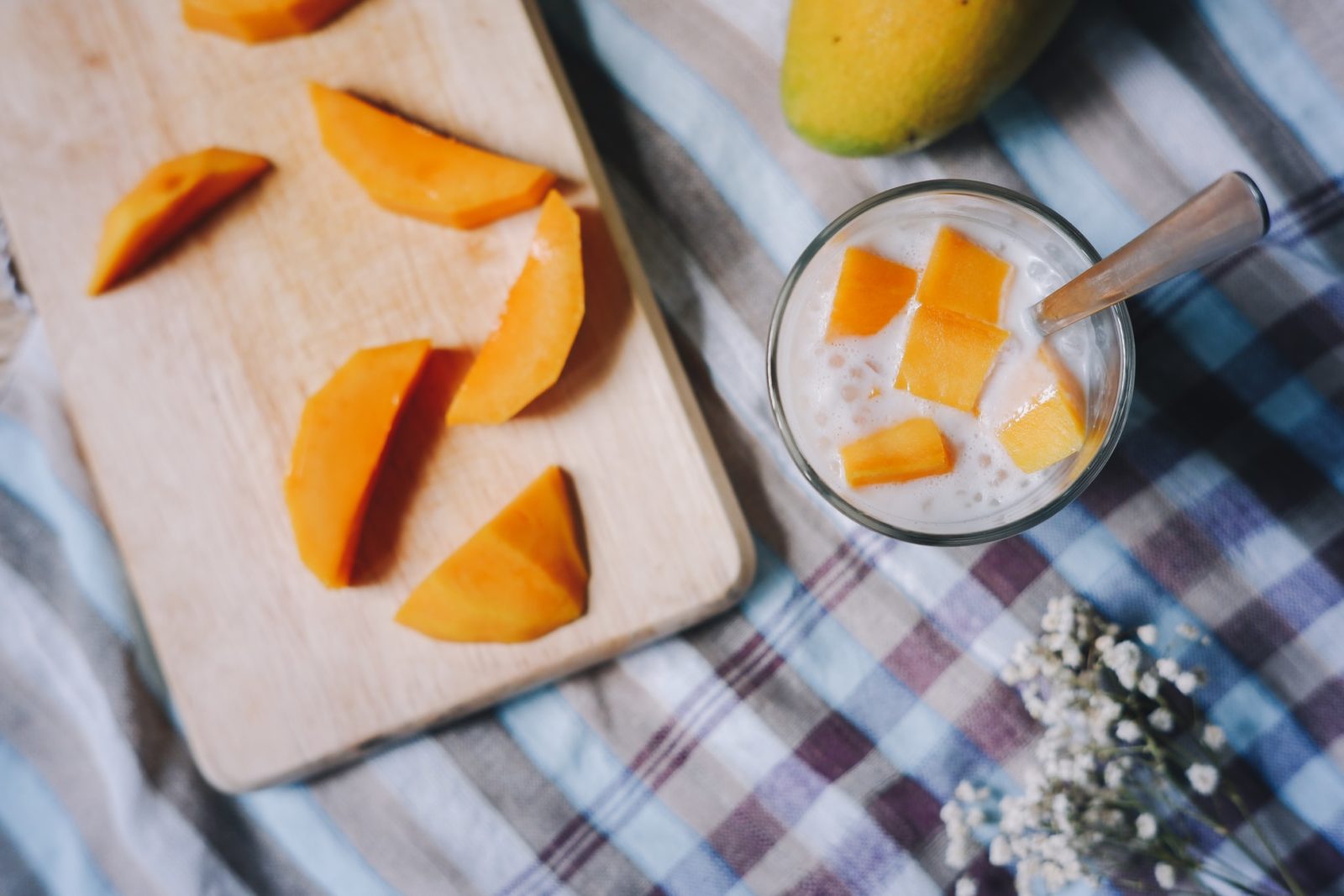 Mango slices on a wooden board next to a mango lassi