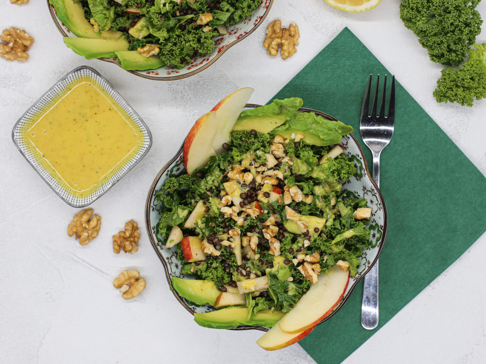 Kale salad with apples and walnuts next to honey mustard dressing