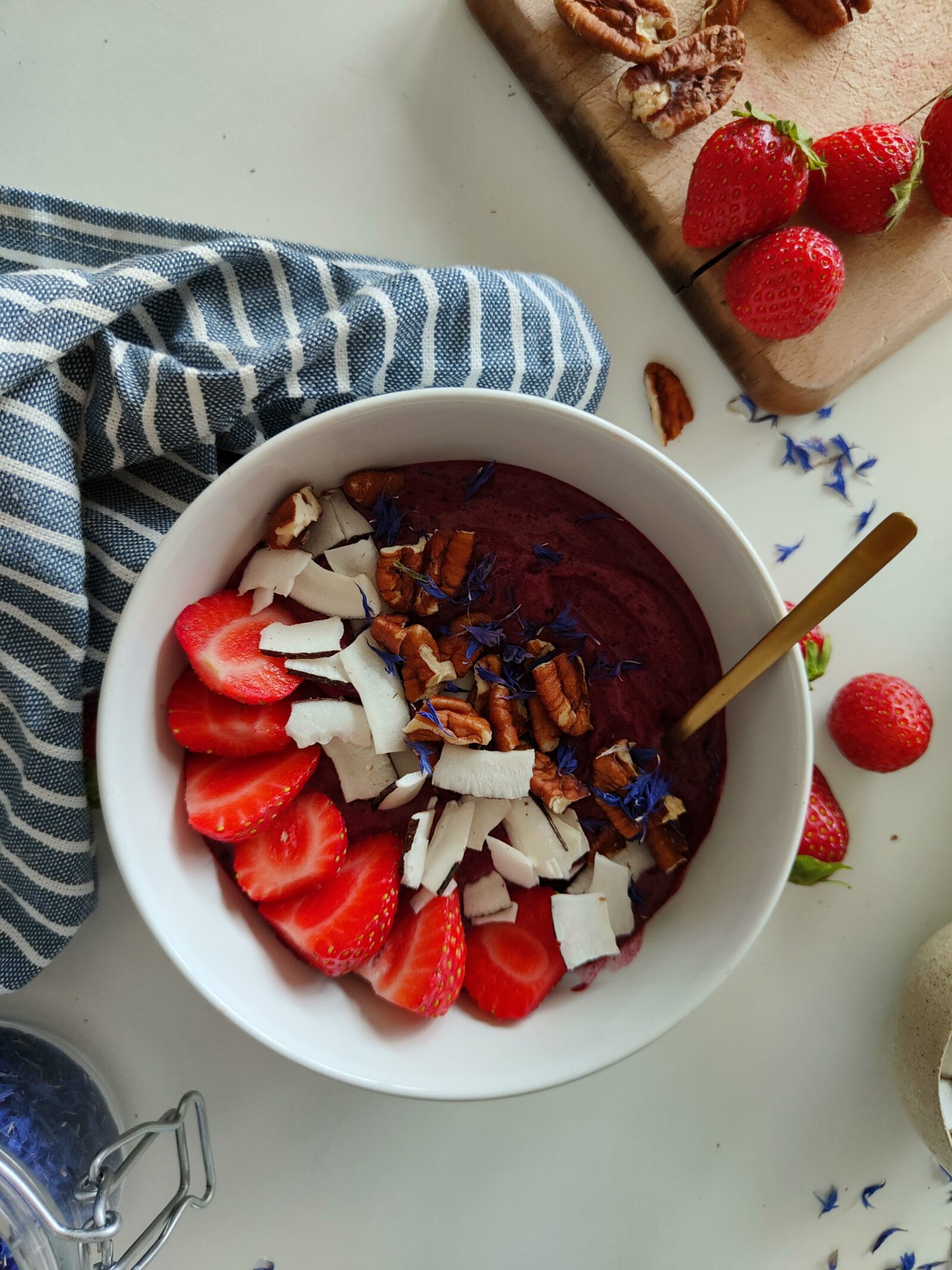 Acai bowl topped with strawberries, coconuts and banana slices