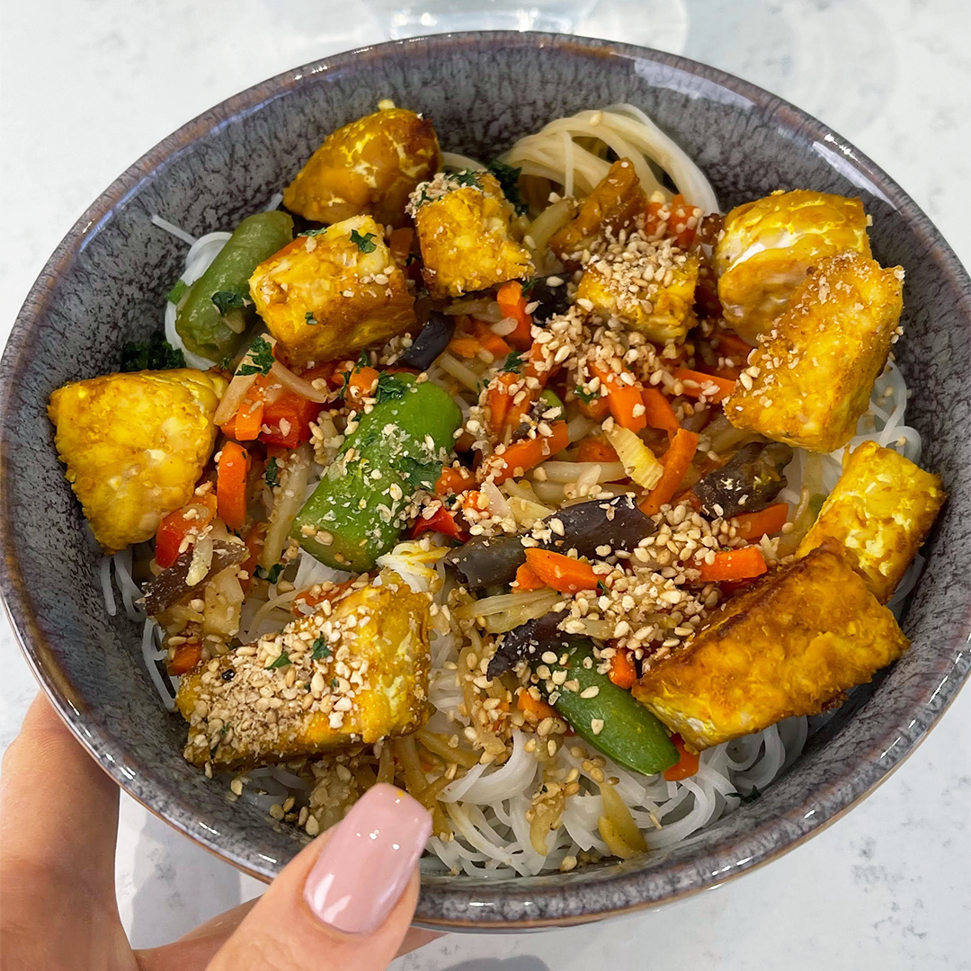 Tempeh and vegetables with rice noodles in a bowl