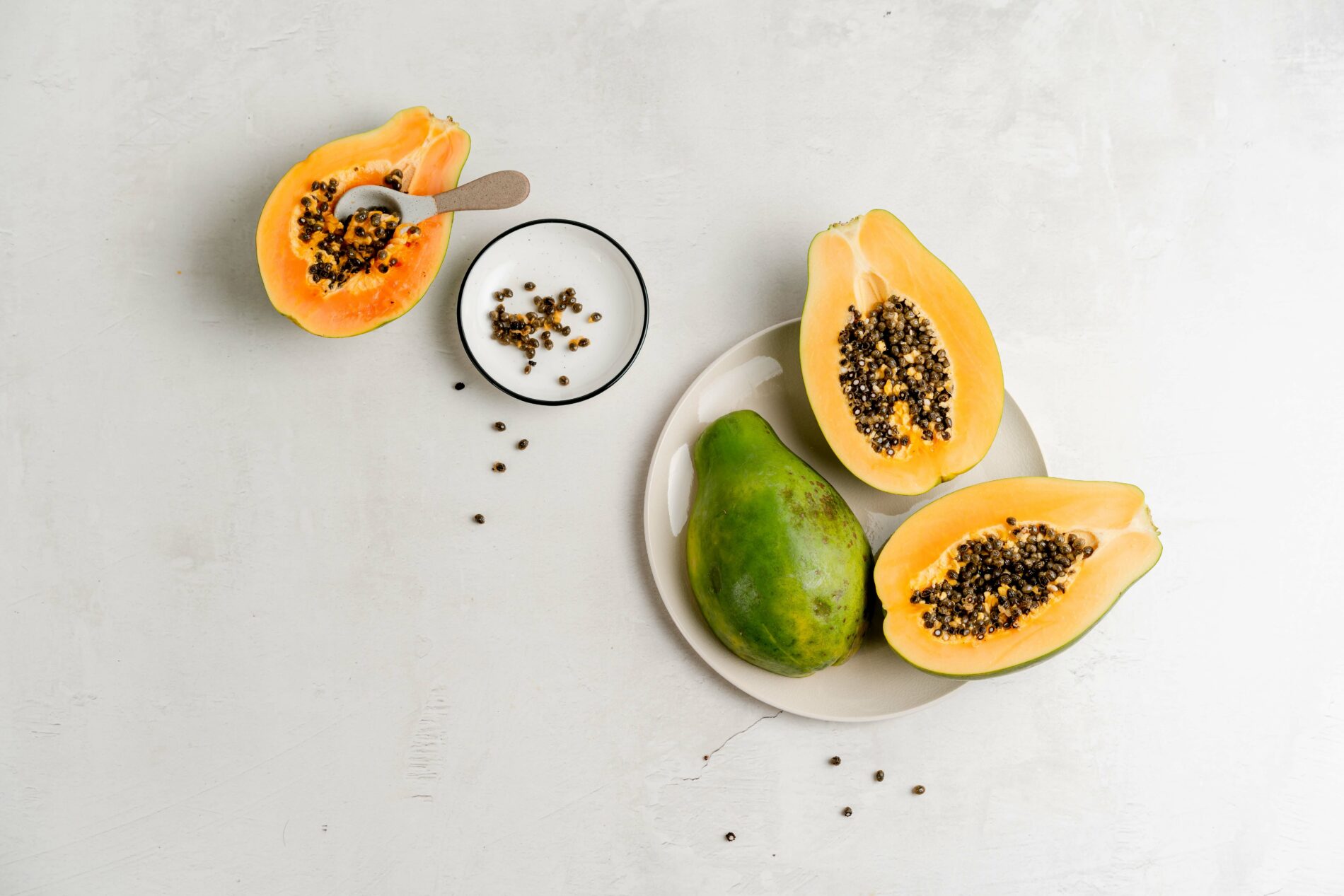 4 halved papayas arranged on white background