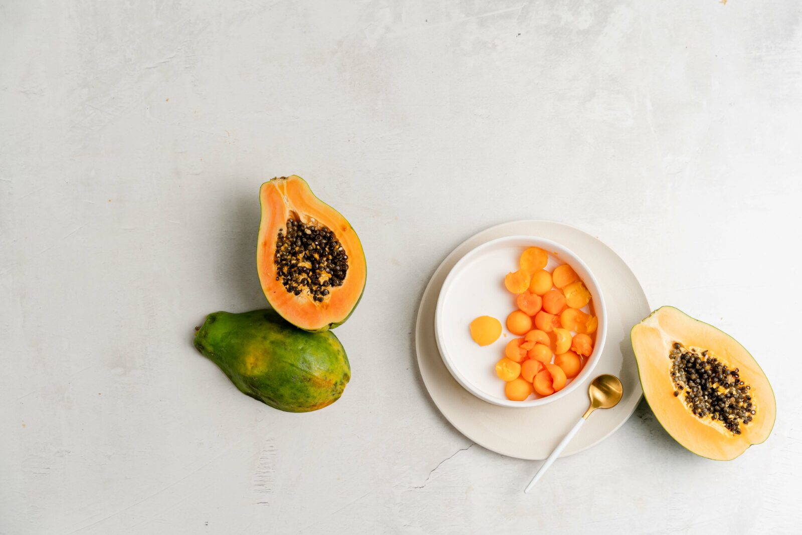 Halved papayas on white marble background