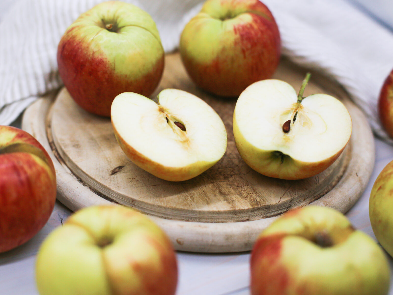 Two halved apples amidst several apples