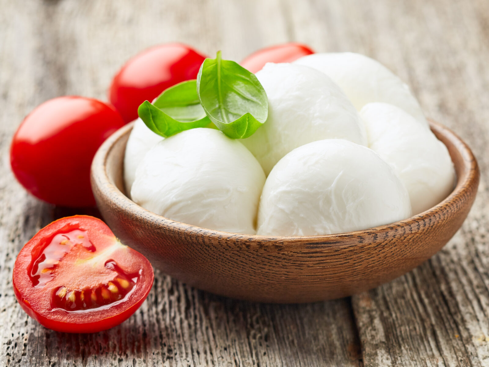 Mozzarella with tomatoes and basil leaves on wooden board