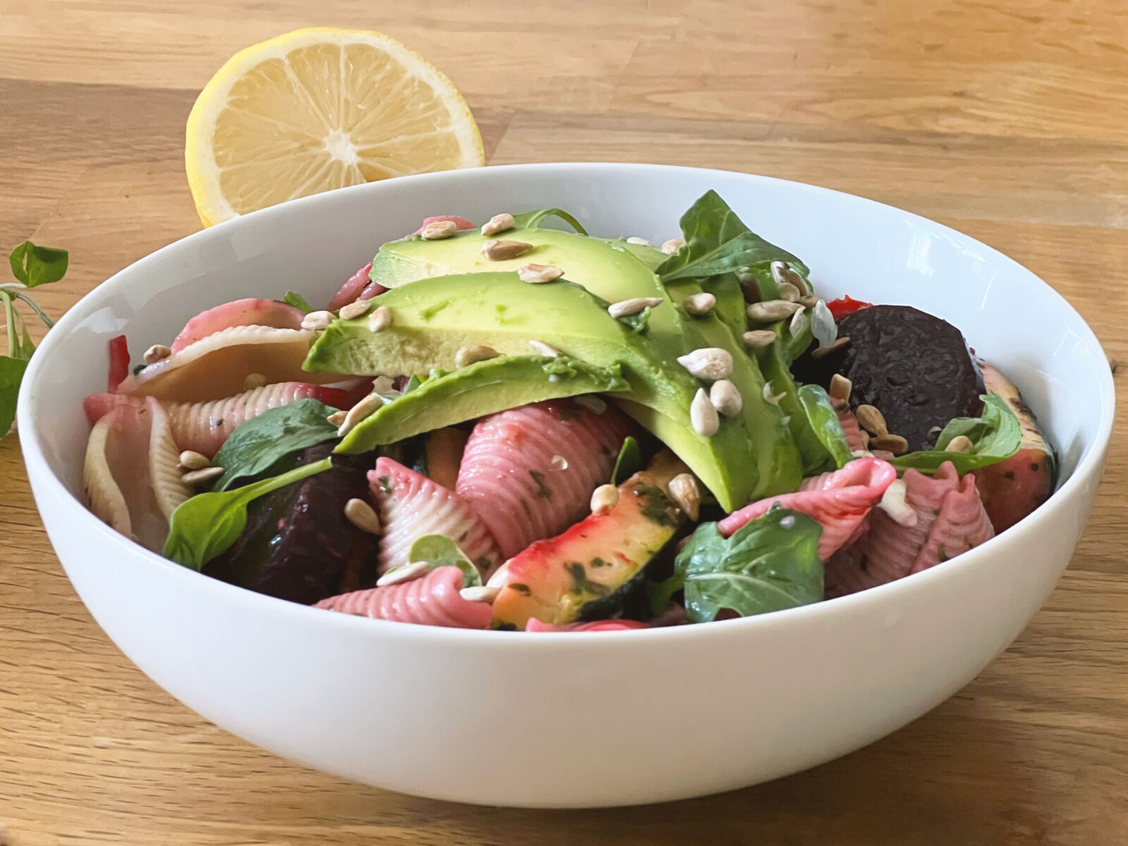 pasta salad with avocado, courgette and beetroots on wooden table