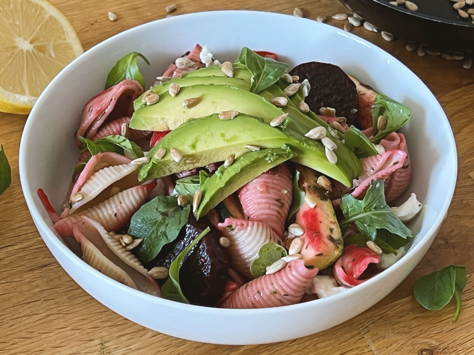 salade de pâtes avec avocat, courgette et betteraves sur une table en bois