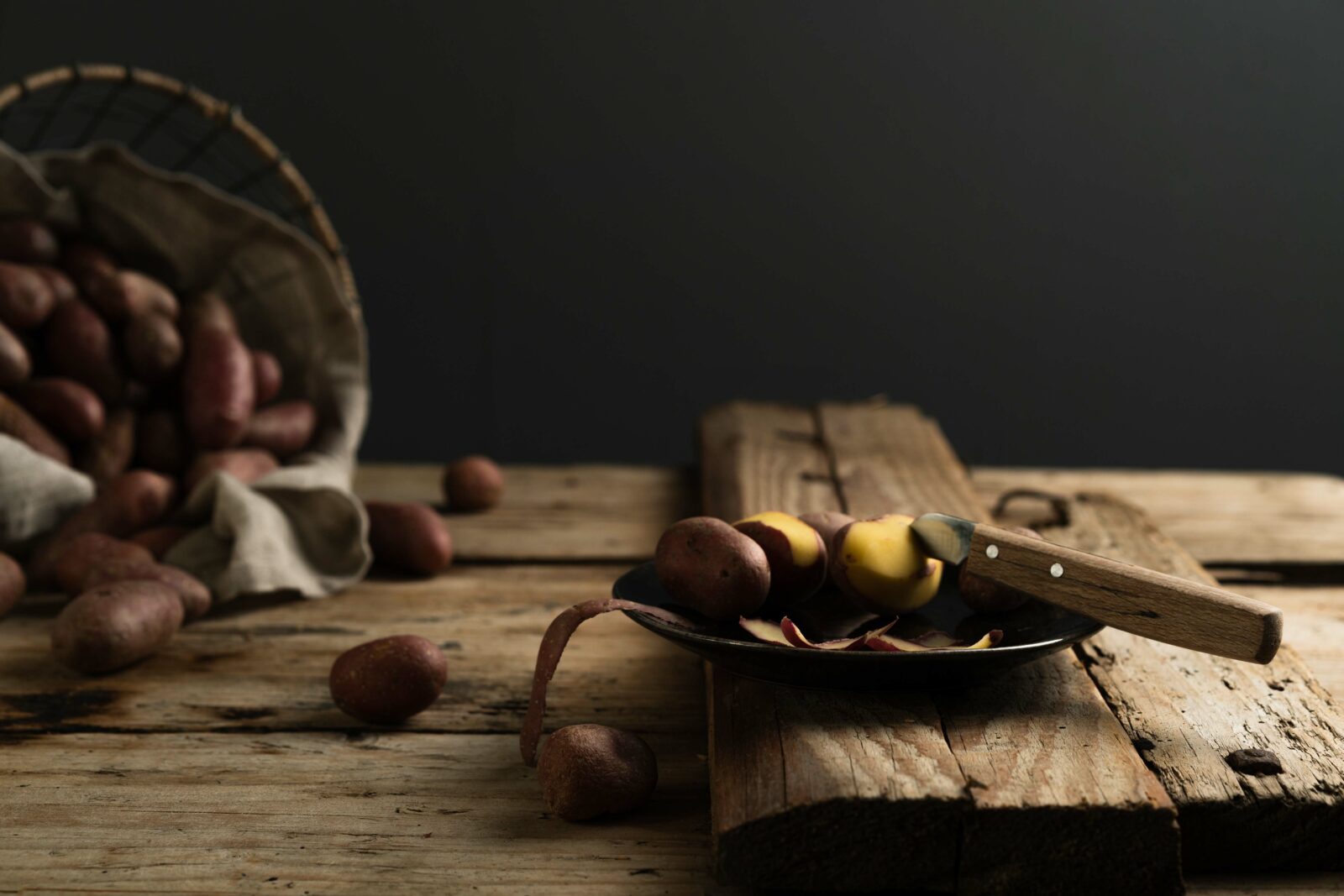 Red potatoes, some of them peeled on a wooden board