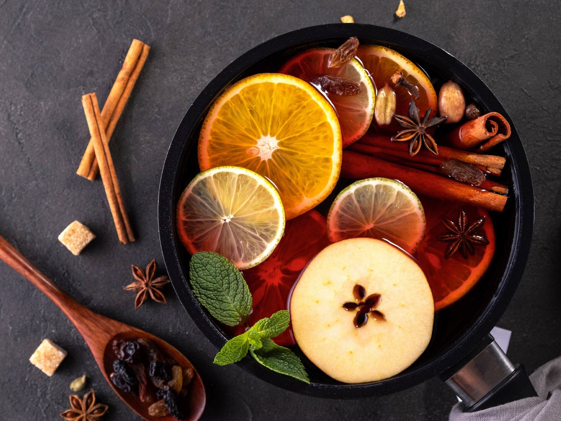 mulled wine in a pan, sliced fruit on top