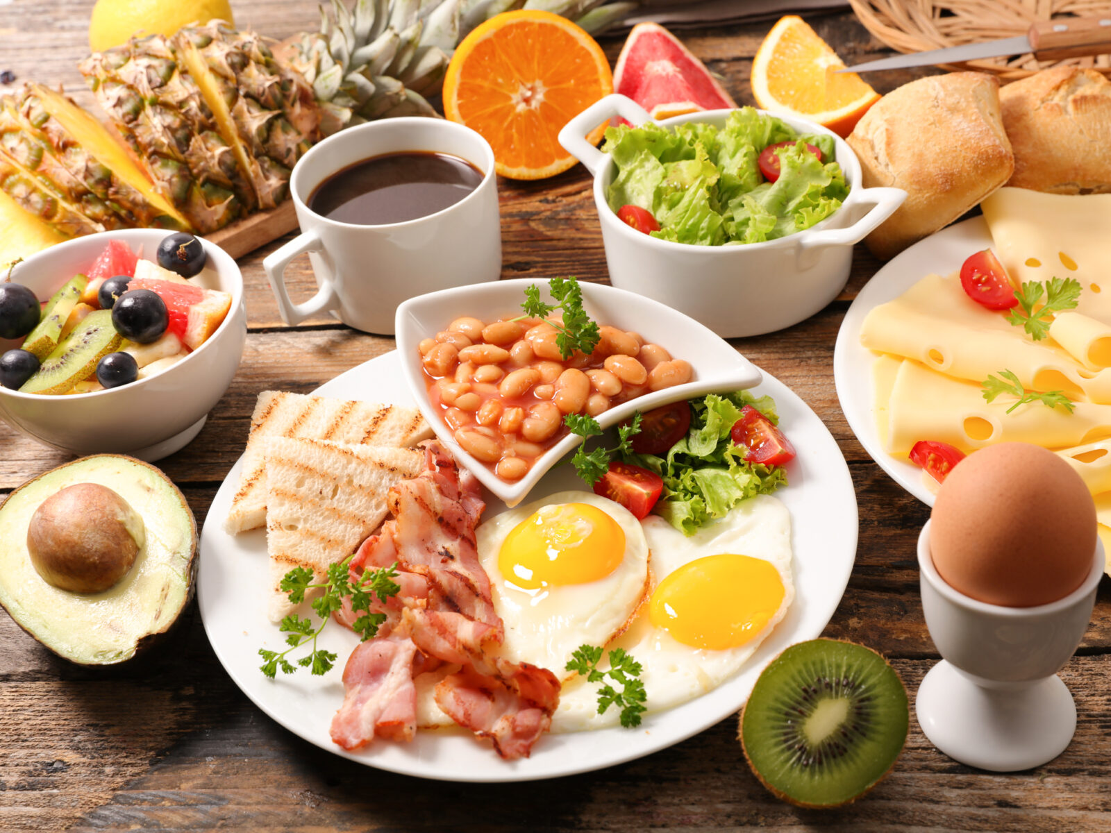 Brunch with eggs, bacon, beans, cheese, fruits and coffee