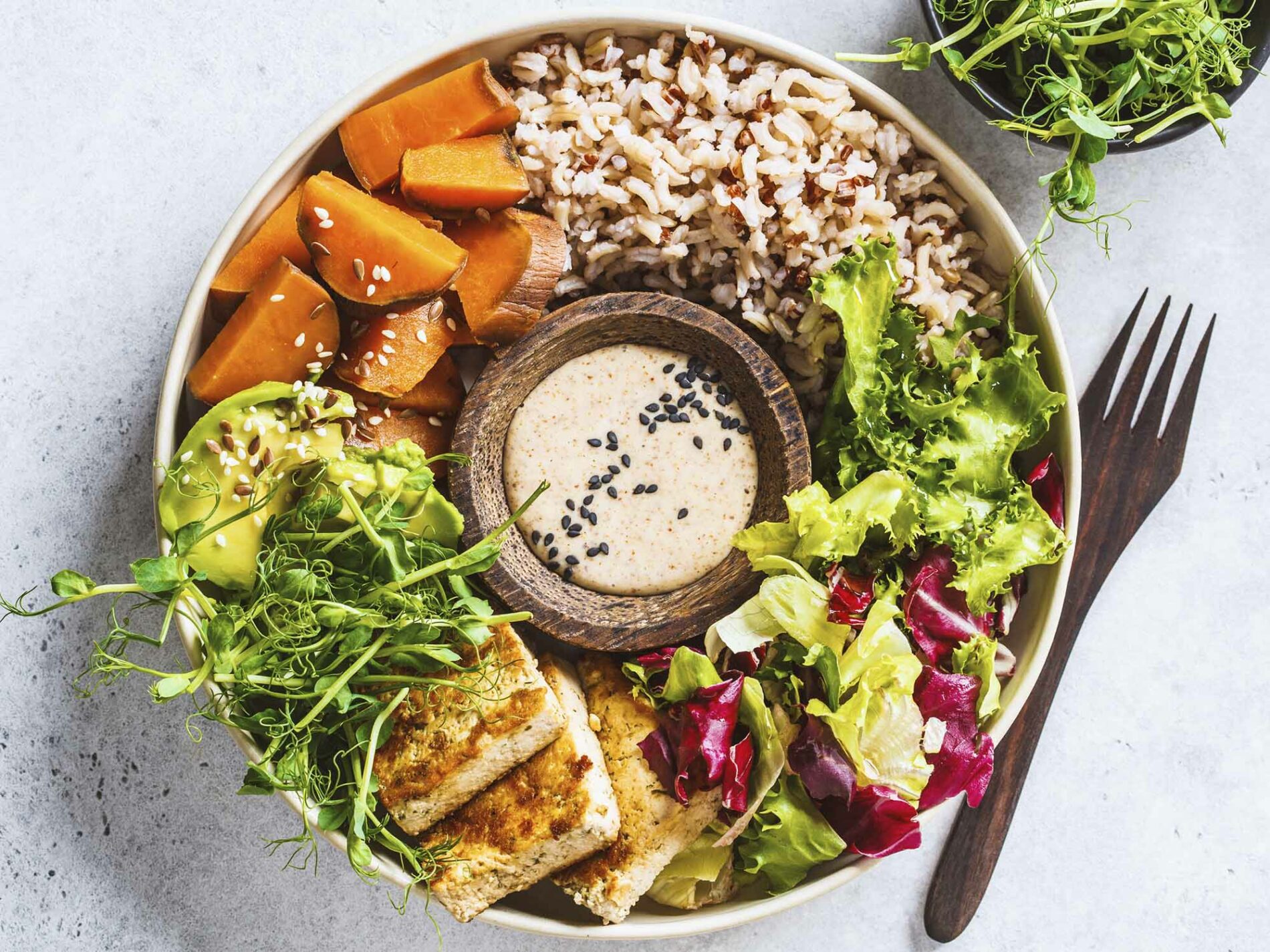 Colourful vegan buddha bowl with dressing in the middle