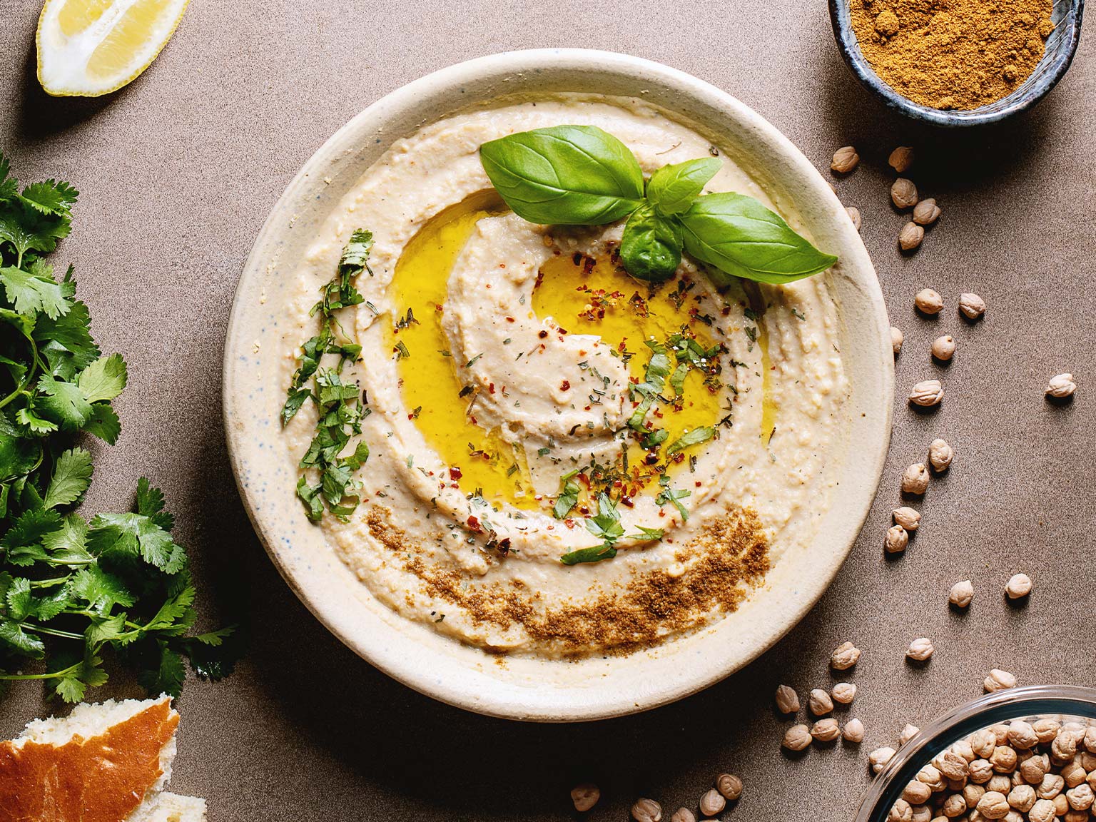 Hummus in a bowl topped with olive oil and basil