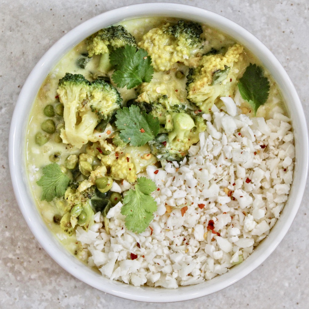 white bowl filled with brocoli, cauliflower rice, cobe and a curry sauce